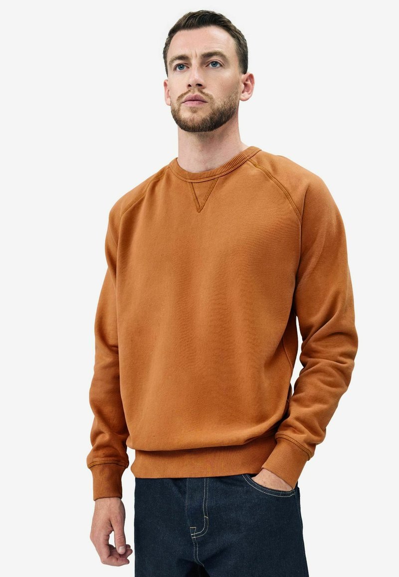 Bruine katoenen sweatshirt met ronde hals en geribbelde boorden, voorzien van een gestructureerd oppervlak en een ontspannen pasvorm. Gemaakt in combinatie met donkere denim jeans.