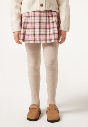 Child wearing beige tights, a pink plaid skirt, cream knit cardigan, and brown suede shoes standing on a white background.