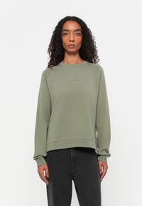 Olijfgroene sweatshirt met een geribbelde ronde hals en lange mouwen. Heeft een subtiele logo op de borst en een relaxte pasvorm. Zachte textuur.
