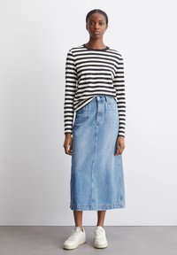 Schwarz-weißen gestreiften Langarmshirt kombiniert mit einem blauen Jeansrock und weißen Sneakers. Einfaches Design, entspannter Schnitt, knielange.