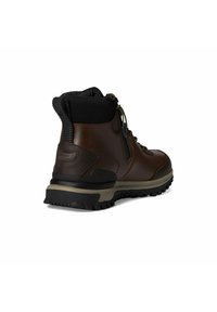 Botte de randonnée imperméable marron avec un orteil renforcé, un col texturé noir, une semelle durable et un système de laçage rapide pour un ajustement sécurisé.
