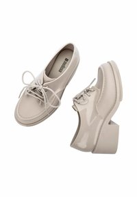 Scarpe in pelle patent beige con punta arrotondata, design con lacci e tacco squadrato spesso. Presentano dettagli di cucitura e una texture liscia.