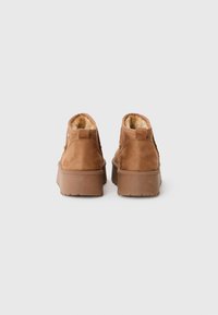Bottines en daim marron avec une doublure en fourrure douce, un dos texturé et une semelle en caoutchouc épaisse avec des motifs de grip.