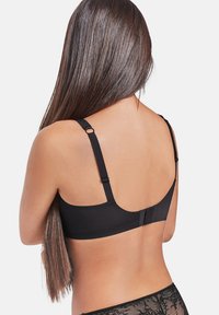 Sostén negro con tirantes ajustables y una tela suave. Cuenta con un cierre de gancho y ojo en la parte posterior y un diseño minimalista.