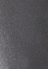 Närbild av grå ribbad tyg med subtila silvermetalliska trådar vävda genom, vilket skapar en texturerad och skimrande effekt.