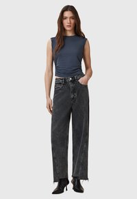 Dark blue sleeveless top with ruched detail, paired with high-waisted black wide-leg jeans featuring a raw hem and front pockets.