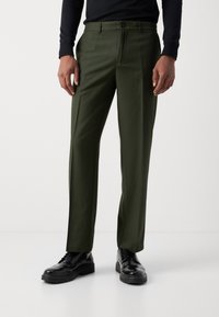 Pantaloni verdi su misura realizzati in tessuto liscio, con vestibilità dritta, tasche tradizionali e chiusura con un bottone.