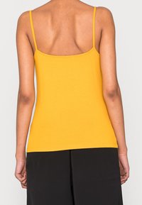 Gul spaghetti strap linne med en figurnära design; slät textur och rak nederkant. Enfärgad, minimal detaljering.