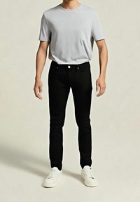 Šedé tričko s krátkým rukávem, kombinované s přiléhavými černými džíny a bílými teniskami. Jednoduchý design bez viditelných vzorů nebo ozdob.