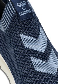 Marineblaue gestrickte Sneaker mit hellblauem Zickzackmuster. Mit einem Markenstoffetikett und einem strukturierten Obermaterial für Atmungsaktivität. Weiße Sohle.
