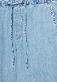 Pantalon en denim bleu clair avec une taille élastique et un cordon noué au centre devant.