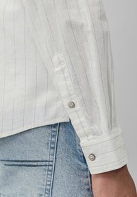 Witte gestreepte linnen shirt met mouw en knoopsluiting, kenmerkend door een textuurstof en casual pasvorm, gecombineerd met lichtblauwe denim.