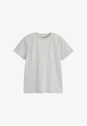 Dreng stående med ryggen til iført en grå t-shirt, sorte shorts med lommedesign, hvide sneakers og hvide sokker med sorte striber.