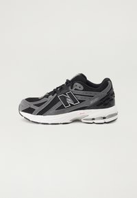Chaussure de sport noire et grise avec tige en mesh, semelle en caoutchouc et détails rembourrés. Comprend des accents de logo et un système de laçage à boucle.
