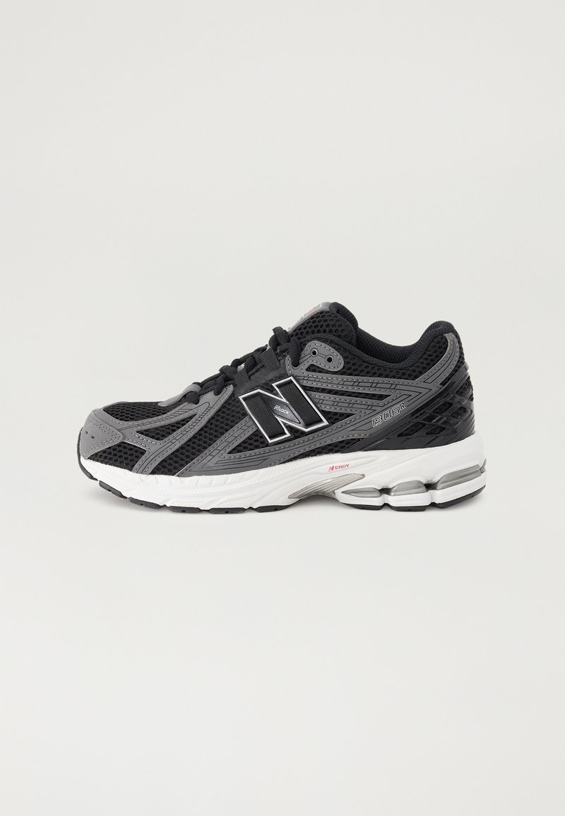 Chaussure de sport noire et grise avec tige en mesh, semelle en caoutchouc et détails rembourrés. Comprend des accents de logo et un système de laçage à boucle.