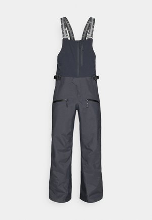 Macacão de esqui cinza escuro com alças ajustáveis, dois bolsos frontais com fecho e um bolso no peito com fecho, feito de um tecido resistente à água.