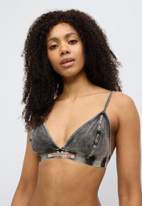 Μαύρο τζιν bralette με τριγωνικά cup, λεπτές τιράντες και ελαστική ταινία με λογότυπο. Ξεθωριασμένη υφή με αντίθετες λεπτομέρειες ραφής.