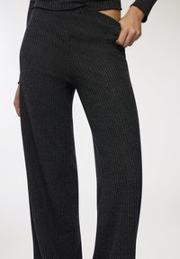 Czarne, prążkowane spodnie szerokie z miękkiej, teksturowanej tkaniny, z wysokim pasem i głównym naciskiem na pionowe paski.
