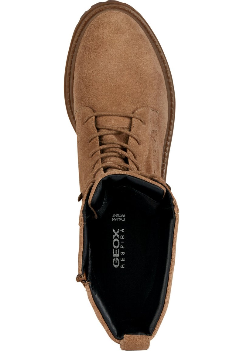 Bruine suède enkellaars met ronde neus, vetersluiting bovenop, gestructureerde zool en zwart voetbed met logodetail.