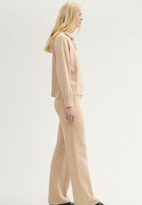 Suéter de punto beige y pantalones de pierna ancha a juego. Textura suave, diseño casual y un ajuste relajado. Estilo simple sin patrones visibles.