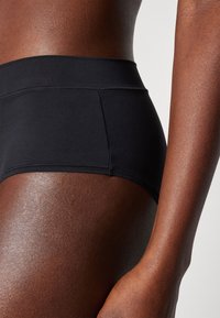 High-waisted black bikini bottoms made from smooth, stretchy fabric, featuring a simple design and seamless edges for comfort.