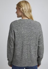 Grå strikket sweater med lange ærmer, rund halsudskæring og en afslappet pasform. Stoffet har en blød tekstur og subtile farvevariationer.