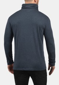 Navyfarbener Langarm-Pullover mit hohem Kragen, aus weichem Stoff, figurbetontem Design und flachen Nähten, das eine glatte Textur präsentiert.