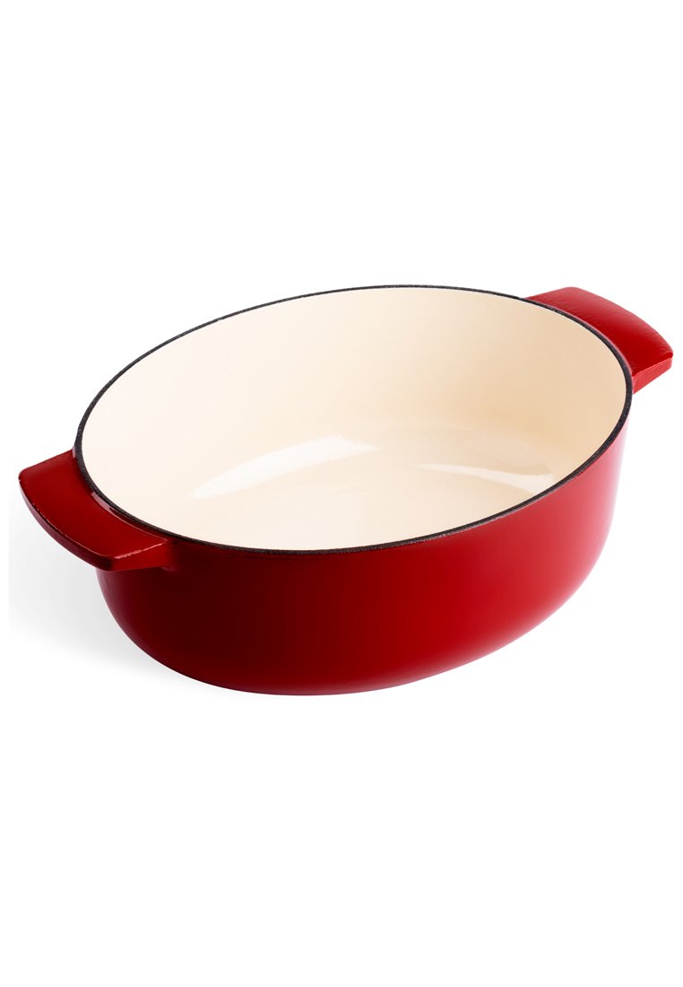 Plato de hornear ovalado de hierro fundido rojo con interior crema, textura suave, dos asas laterales y un acabado brillante. Bisel redondo con borde negro.