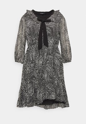 Schwarzes knielanges Kleid mit weißem unregelmäßigem Punktemuster, transparenten Puffärmeln, gerafftem Kragen und schwarzer Schleife am Ausschnitt.