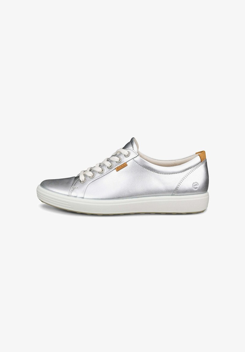 Srebrny sneaker z refleksyjnym metalicznym wykończeniem, biała gumowa podeszwa, sznurowany design i mały beżowy akcent na pięcie.