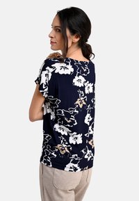 Navy floral blouse featuring white and beige flowers, lightweight fabric, relaxed fit, short sleeves, and a round neckline.