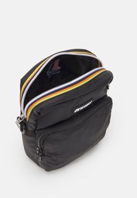 Schwarze Nylon-Tasche mit drei Reißverschluss-Fächern, die bunte Streifen an den Reißverschlüssen aufweist, und eine Fronttasche mit markenspezifischer Hardware.