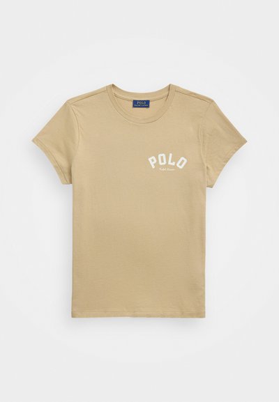 Beżowa koszulka z krótkim rękawem wykonana z bawełny, z okrągłym dekoltem i białym nadrukiem logo z napisem „POLO” nad „Ralph Lauren”.