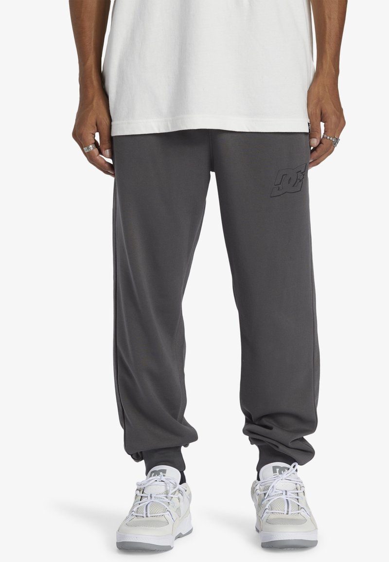 Gray sweatpants made of soft fabric with an elastic waistband and cuffed ankles. Features a subtle logo on the thigh.