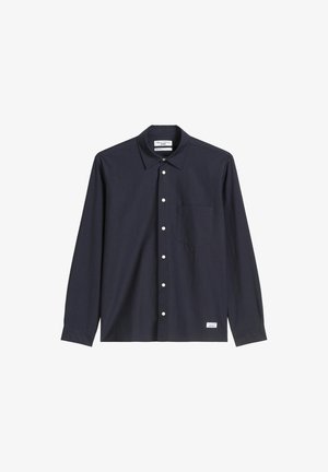 Granatowa koszula zapinana na guziki, wykonana z tkaniny o splocie, z klasycznym kołnierzykiem, długimi rękawami, kieszenią na piersi oraz małą metką na dolnym brzegu.