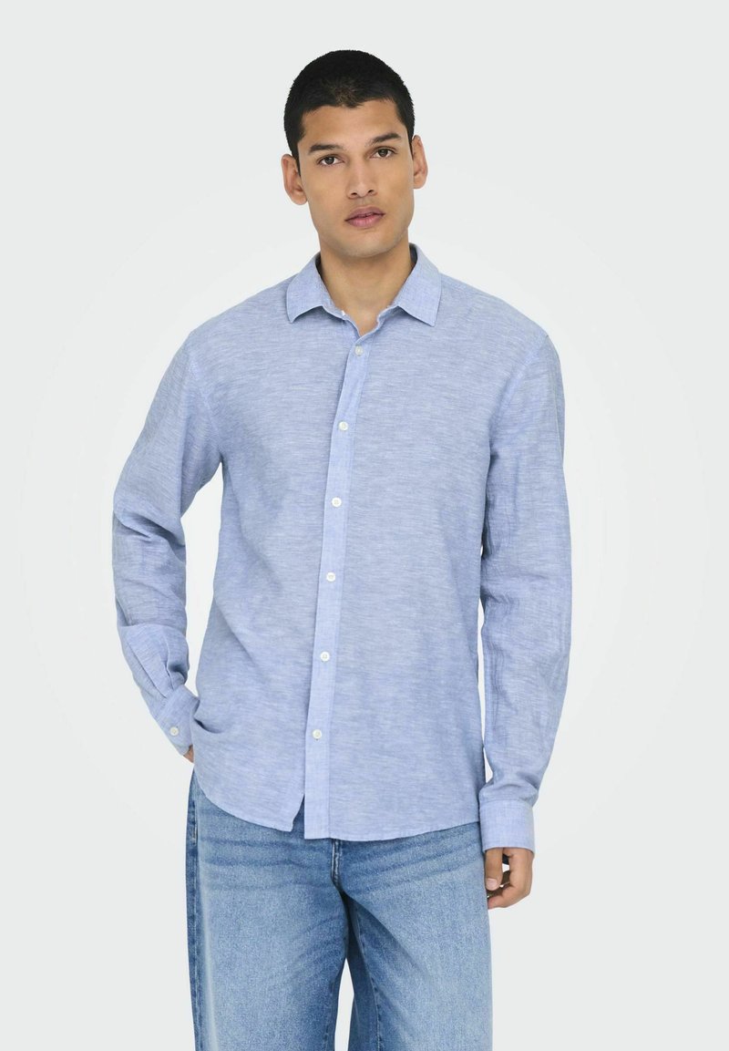 Camicia azzurra chiara con bottoni, realizzata in tessuto misto lino, con colletto, maniche lunghe e bottoni bianchi.