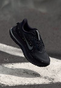 Schwarzer Sportschuh mit Obermaterial aus Netzgewebe und weißen sprenkelnden Akzenten. Verfügt über ein silbernes Swoosh-Logo und eine strukturierte Sohle mit Grippatterns.