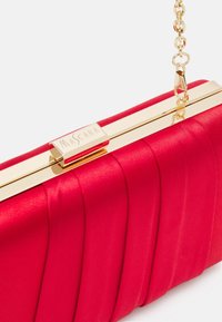 Pochette en satin rouge avec un cadre en métal doré et une chaîne, dotée d'un design plissé et d'un détail de logo sur le fermoir.