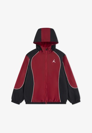 Chaqueta cortaviento roja y negra con capucha, cierre frontal con cremallera y ribetes blancos. Presenta un logo en el pecho y puños elásticos. Tela ligera.