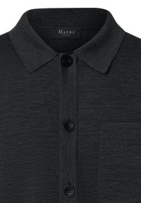 Mörkgrå stickad polo med krage, fem knappar och bröstficka. Har en jämn textur och en strukturerad design.