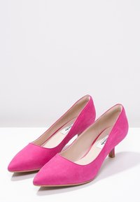 Chaussures à talons hauts en daim rose avec un bout pointu et un talon court et fin. Texture lisse et style minimaliste.