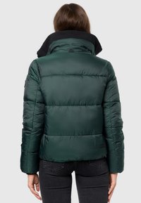 Puff jacket in dark green with a high collar. Made of smooth, shiny fabric, features horizontal quilting and a small logo on the back.