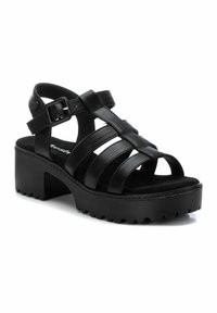 Sandalias de plataforma de cuero negro con múltiples tiras, hebilla ajustable y suela texturizada para mayor agarre. Diseño de punta abierta y plantilla acolchada.