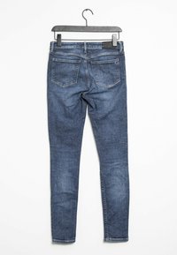 Tmavě modré džíny skinny s zadními kapsami, poutky na opasek a hladkým povrchem, visící na černém plastovém ramínku.