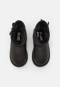 Botines de concha blanda negros con un exterior texturizado y suave. Forro de felpa y una pestaña para ponerlos fácilmente. Diseño de punta redondeada y tobillo bajo.