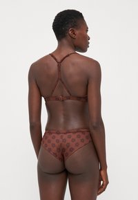 Braun gemustertes Unterwäsche-Set mit floralem Muster, bestehend aus einem Racerback-Design mit verstellbaren Trägern und glatter Textur. Die Rückansicht zeigt eine gute Abdeckung.