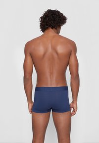 Marineblå boxertruser laget av myk stoff, med elastisk midje og en tettsittende design som gir komfort og støtte.