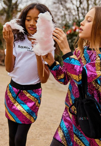 Twee kinderen houden suikerspin vast. De ene draagt een wit shirt en een multicolor paillettenrok. De andere draagt een bijpassend pailletten topje en zwarte leggings.