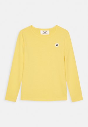 Geel katoenen shirt met lange mouwen, ronde hals en een klein wit rond logo met een zwarte "W" op de linkerborst.