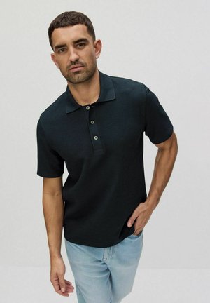Sort kortærmet polo t-shirt med struktureret stof, tre-knaps placket og flad krave, parret med lyseblå jeans.